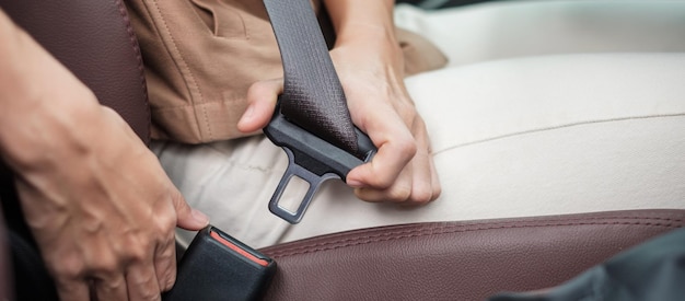 Woman driver hand fastening seat belt during sitting inside a car and driving in the road safety trip journey and transport concept