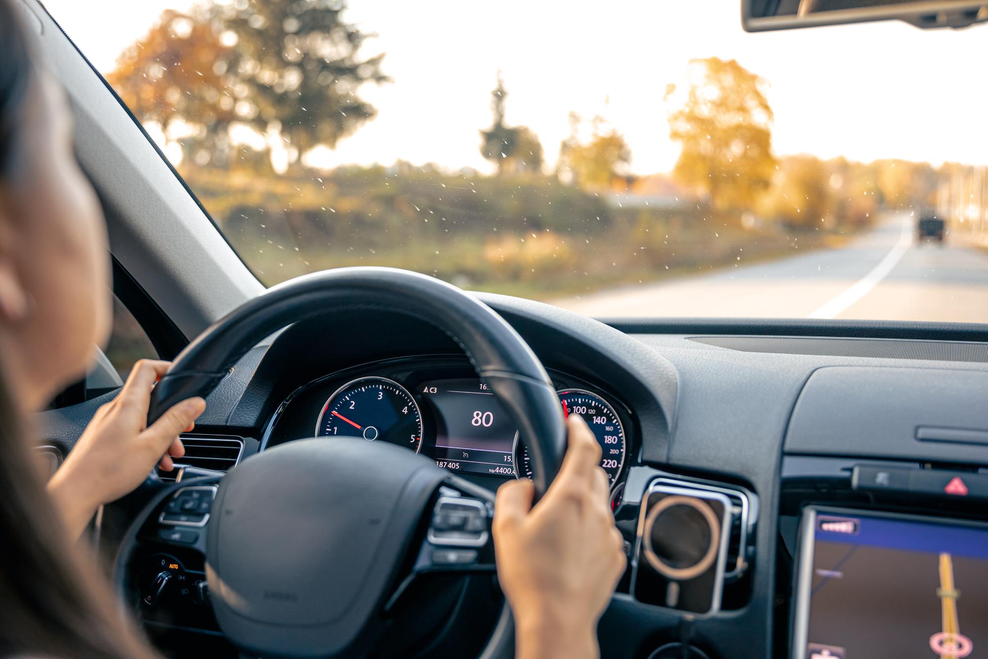 Woman driver hands on steering wheel inside car