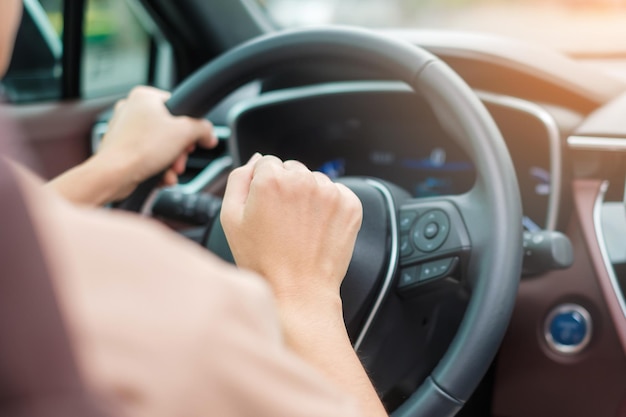 車の中でハンドルを制御する交通道路の手で運転中に車を鳴らしている女性ドライバー旅の旅と安全輸送の概念