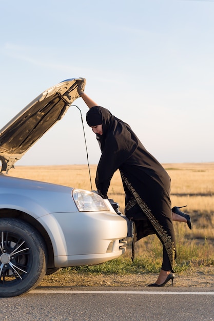 Woman driver opens the hood of a car for the first time.