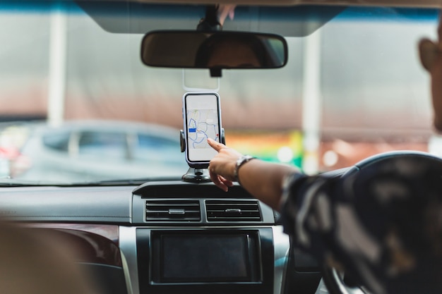 Photo woman driver using gps navigation in mobile phone while driving car.