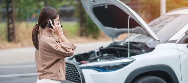 Autista donna che utilizza il telefono cellulare durante l'auto problematica guasto o auto rotta su strada concetto di manutenzione e servizio dell'assicurazione del veicolo