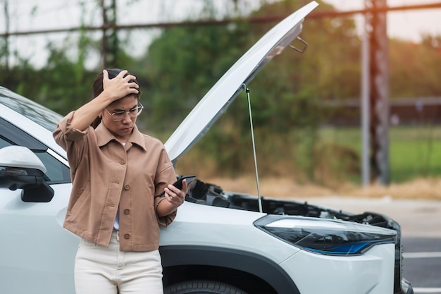 問題のある車の故障または道路上の壊れた車の間に携帯電話を使用している女性ドライバー自動車保険のメンテナンスとサービスの概念