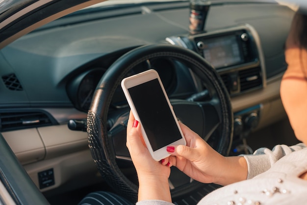 교통 체증 동안 자동차에서 스마트 폰을 사용하는 여성 운전자, 디자인 목적으로 빈 화면.