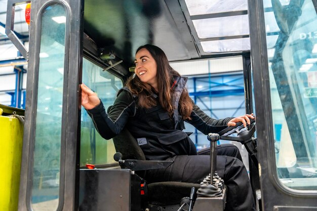 Foto donna alla guida di un carrello elevatore in una fabbrica