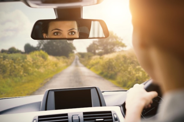 Foto donna alla guida con il suo riflesso nello specchio della sua auto