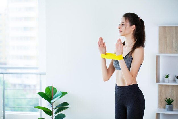 Woman during her fitness workout at home with rubber resistance\
band