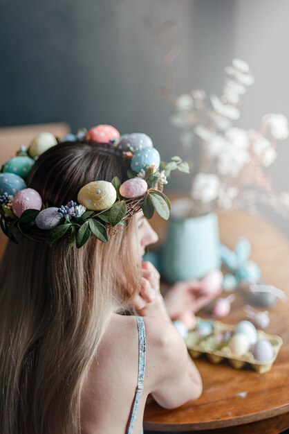 Woman in easter wreath at the table with easter eggs