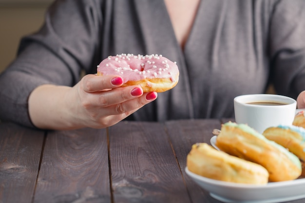 女性はドーナツを食べて、コーヒーを飲む