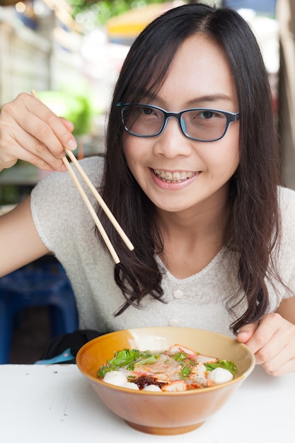 女性はヌードルを食べる。