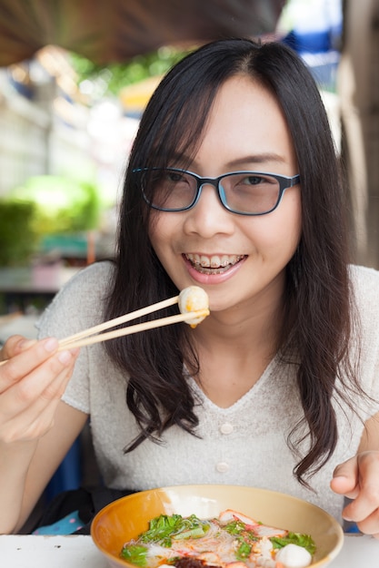 女性はヌードルを食べる。