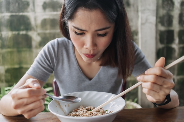 女性は地元の通りで箸で辛い麺を食べる