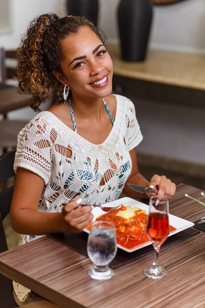 肉と麺のパルミジャーナのおいしい料理を食べる女性。