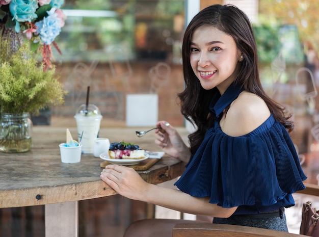 カフェでブルーベリーチーズケーキを食べている女性