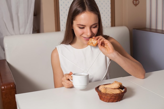 カフェでクッキーを食べて熱いお茶を飲む女性