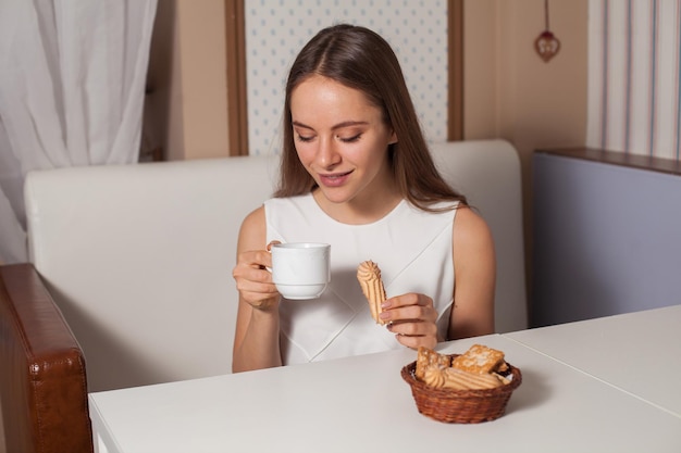 Woman eating cookies and drinking hot tea in cafe