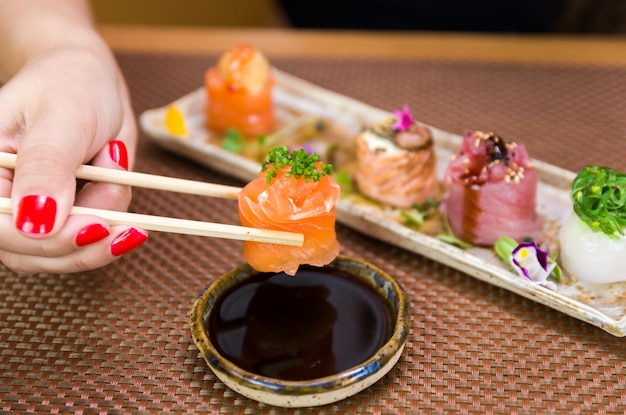 Woman eating delicious gunkan sushi closeup on chopsticks