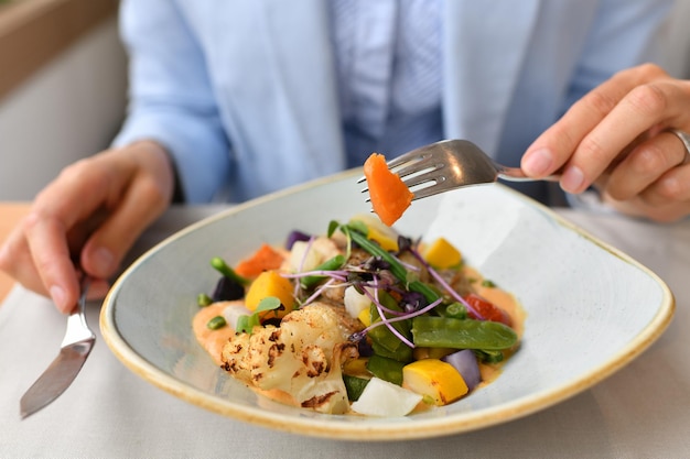 A woman eating fish with vegetables in a restaurant