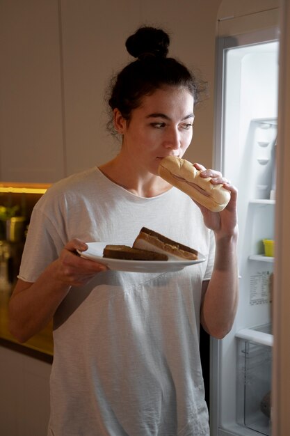 Photo woman eating food from the fridge