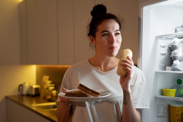 Photo woman eating food from the fridge