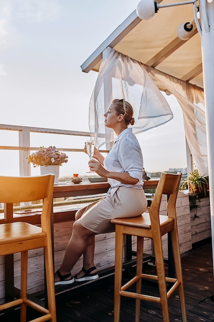 Woman eating fresh oysters and drinking chilled prosecco wine on the summer sunset Seafood delicacies