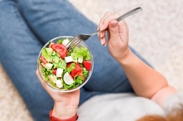 Woman eating fresh vegetable salad top view