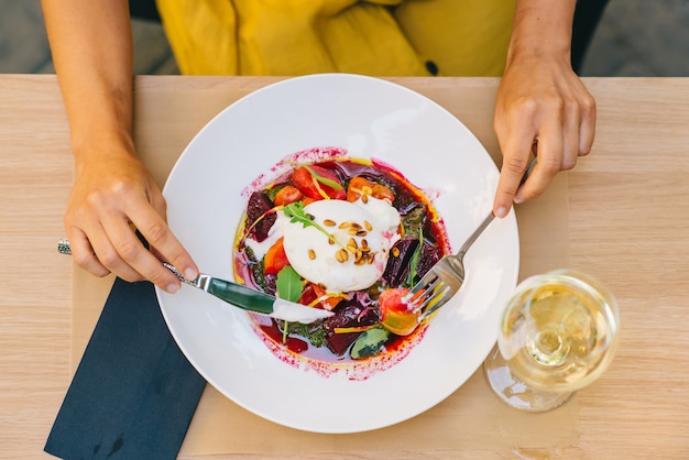 사진 burrata 치즈, arugula 및 비트 뿌리 샐러드와 건강 샐러드를 먹는 여자