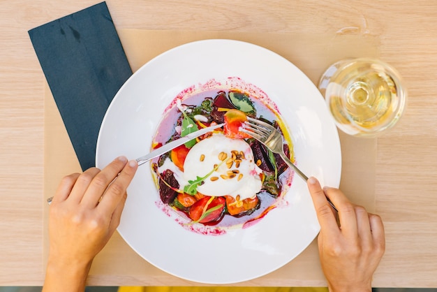 Foto donna che mangia insalata sana con formaggio burrata, rucola e insalata di barbabietole