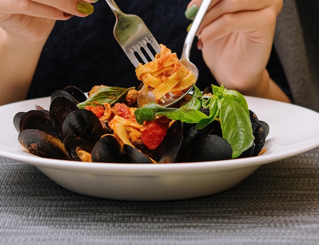 Woman eating pasta with mussels in a restaurant