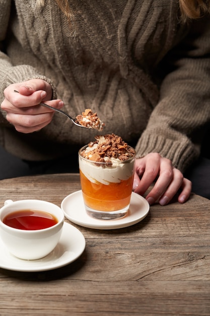 柿プディングを食べる女性。ヨーグルトクリームとチョコレートと柿のスムージーで朝食をとっている女性