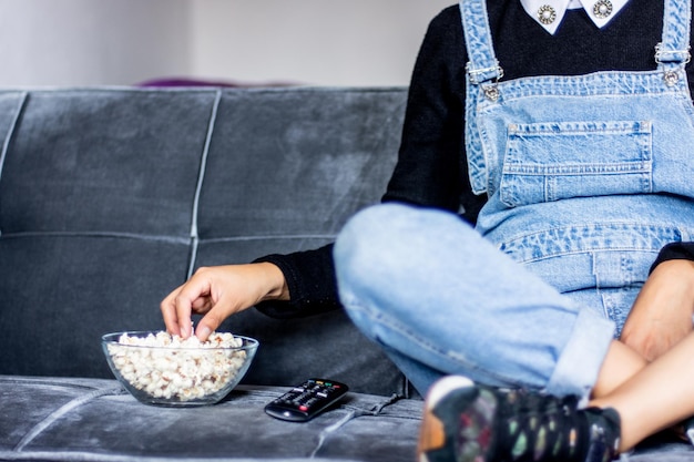 家で映画を見ながらポップコーンを食べる女性