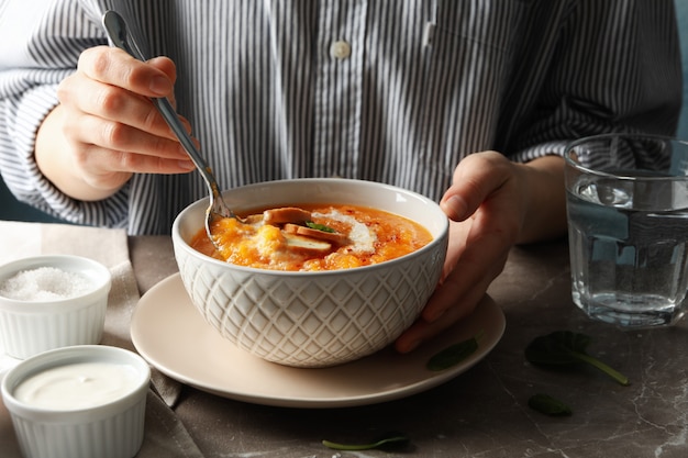 灰色のテーブルにカボチャのスープを食べる女をクローズアップ