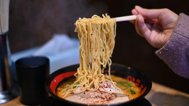 箸でラーメンを食べる女性