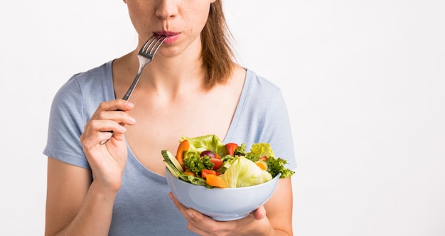 Foto donna che mangia un'insalata con una forchetta