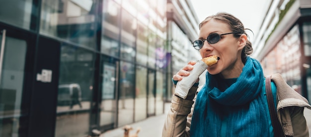 Woman eating sandwich and walking