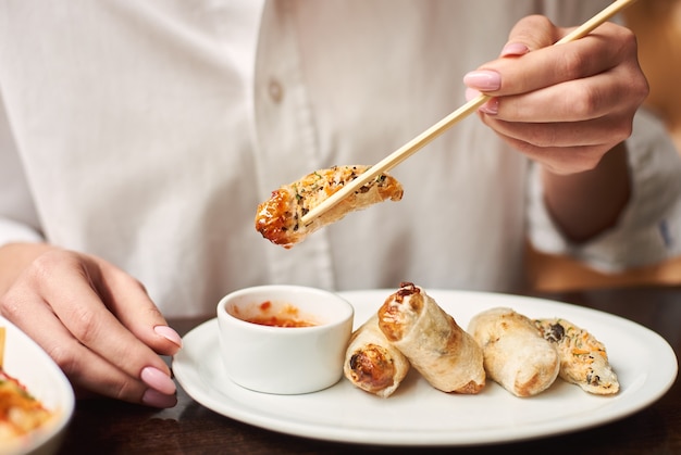 Donna che mangia una gustosa cena orientale nel ristorante asiatico.