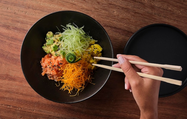 Woman eating traditional hawaiian dish poke bowl with fork diet and useful fast food