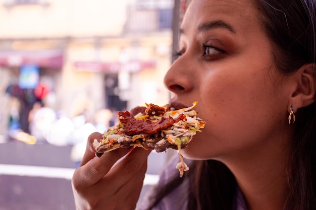 Woman eating a traditional Mexican food tlayuda made of tortilla with beans and meat