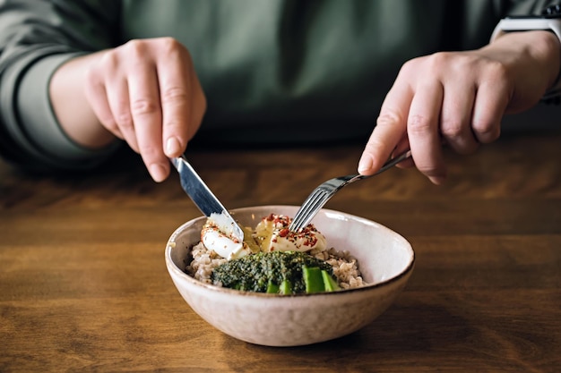 Woman eating vegetarian salad in cafe healthy bowl with buckwheat poached egg and avocado sauce