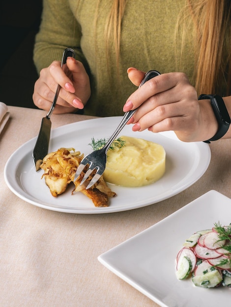 woman eats her lunch in restaurant fish and chips and salad with radish