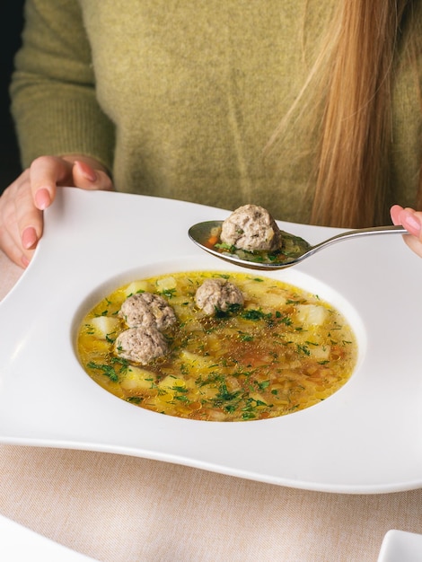 女性はレストランの白いスープで彼女の昼食を食べる