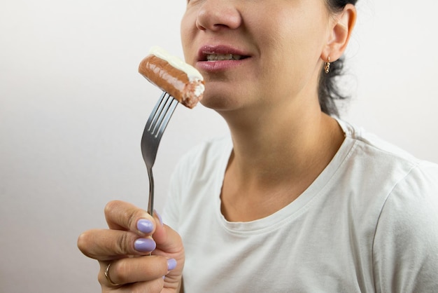 Woman eats sausage on a fork Closeup