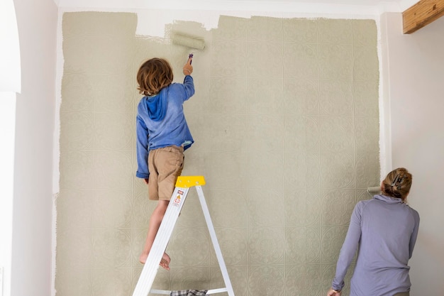 A woman and an eight year old boy decorating a room painting walls