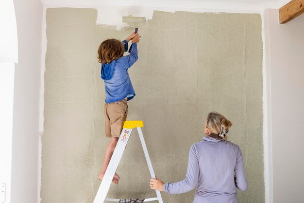 A woman and an eight year old boy decorating a room painting walls