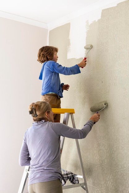 A woman and an eight year old boy decorating a room painting walls