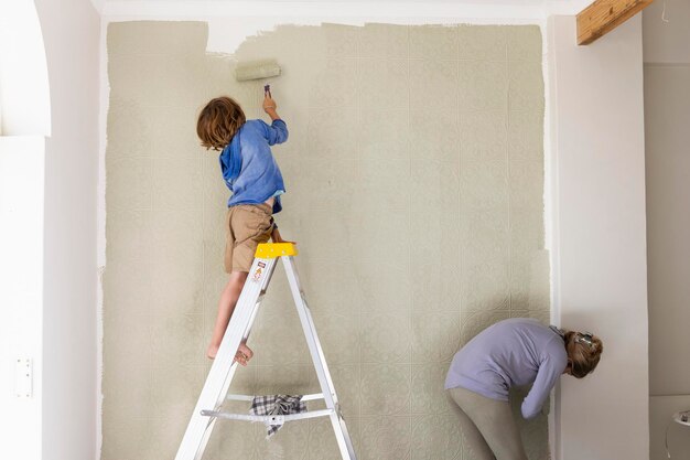 Foto una donna e un bambino di otto anni decorano le pareti di una stanza