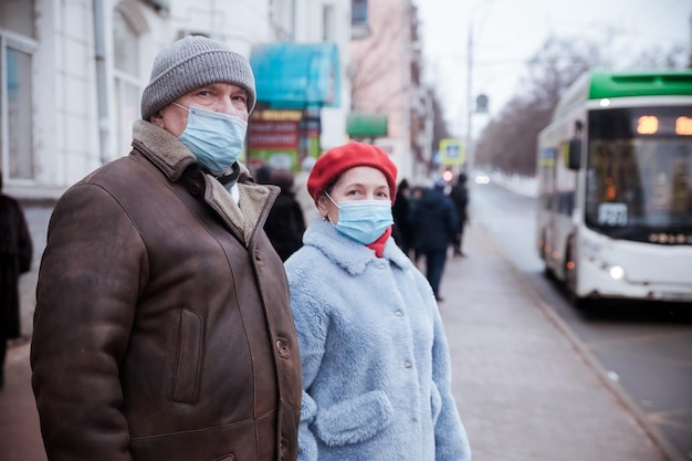 Woman and elderly man in protective medical masks on street