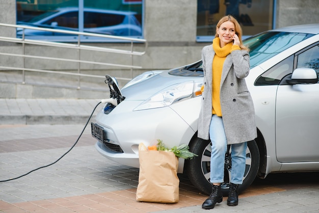 Woman on the electric cars charge station at daytime