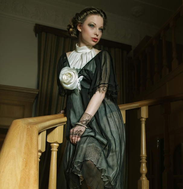 Woman in elegant dress posing on stairs