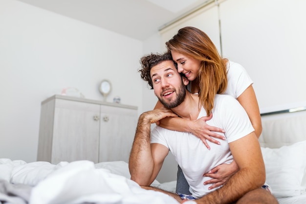 Woman embracing her partner in bed, happy couple in bed showing\
emotions and love. beautiful loving couple kissing in bed.\
beautiful young couple lying together on the bed.